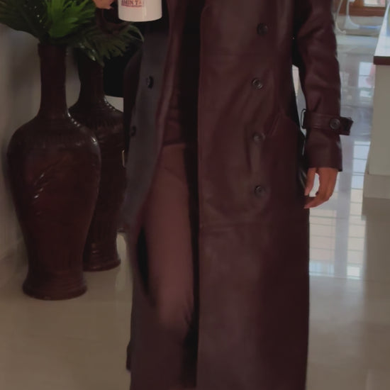 A close-up video of the Burgundy Genuine Leather Trench Coat, focusing on the lapel collar, wrist straps, shoulder details, and side pockets. The video demonstrates the high-quality craftsmanship, including the adjustable belt and fully lined interior.