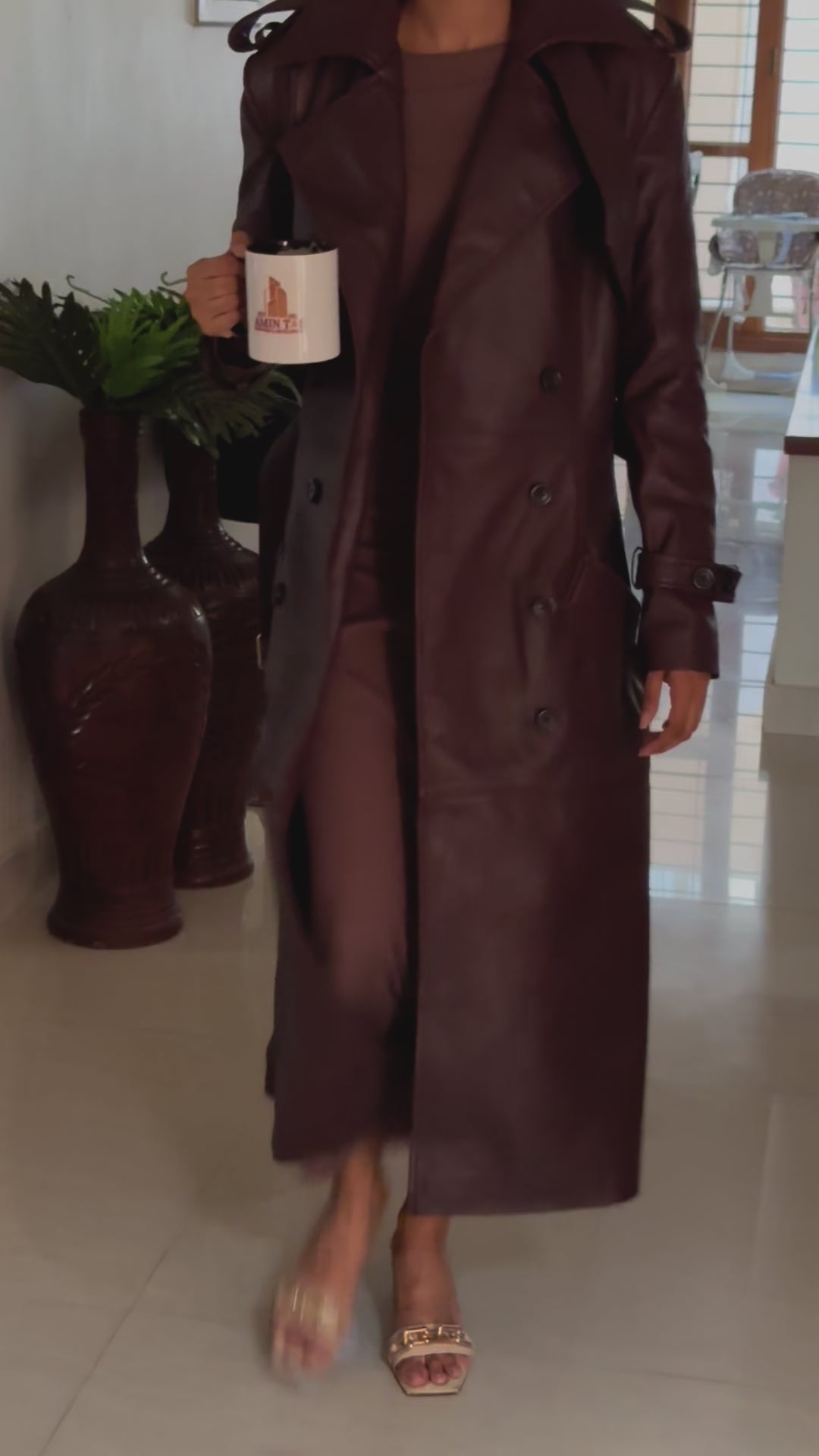 A close-up video of the Burgundy Genuine Leather Trench Coat, focusing on the lapel collar, wrist straps, shoulder details, and side pockets. The video demonstrates the high-quality craftsmanship, including the adjustable belt and fully lined interior.